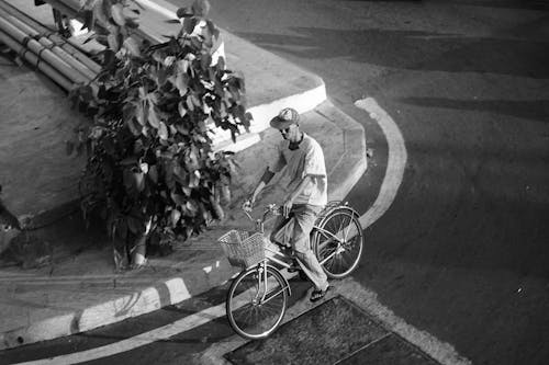 A black and white photo of a man riding a bike