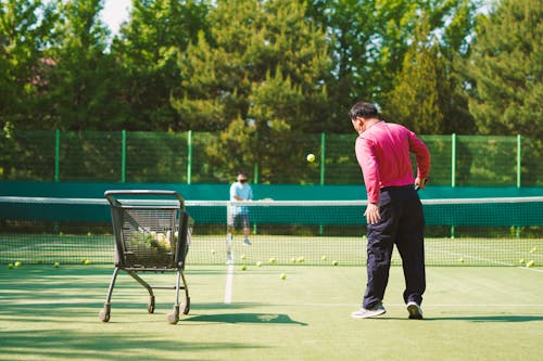A man is playing tennis on a green court