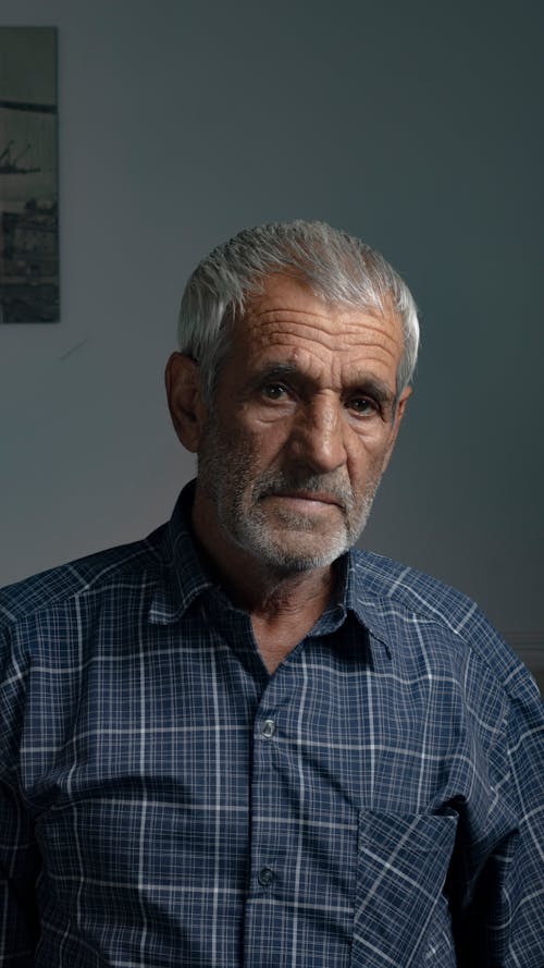 An older man in a plaid shirt and a blue shirt