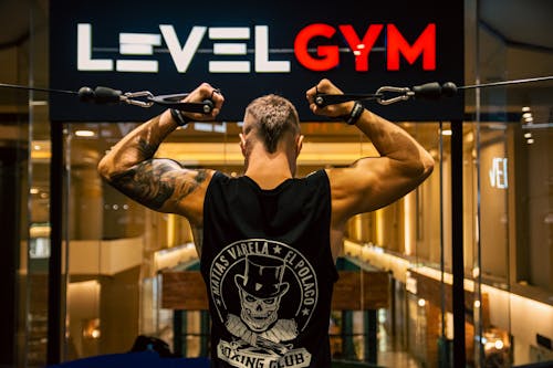 A man with his arms up in the air in front of a level gym sign