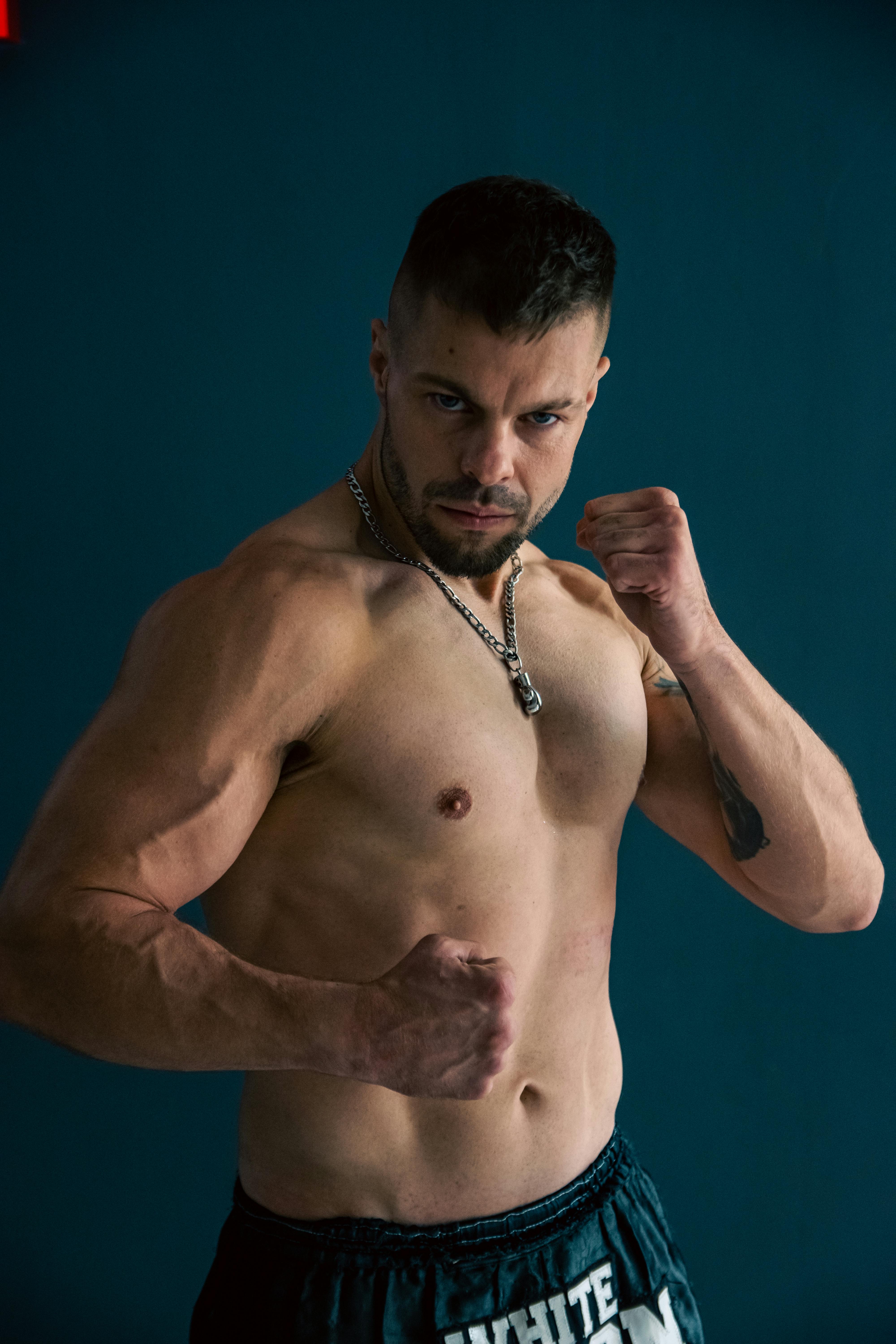 Shirtless athlete posing in martial arts stance, showcasing strength and muscles.