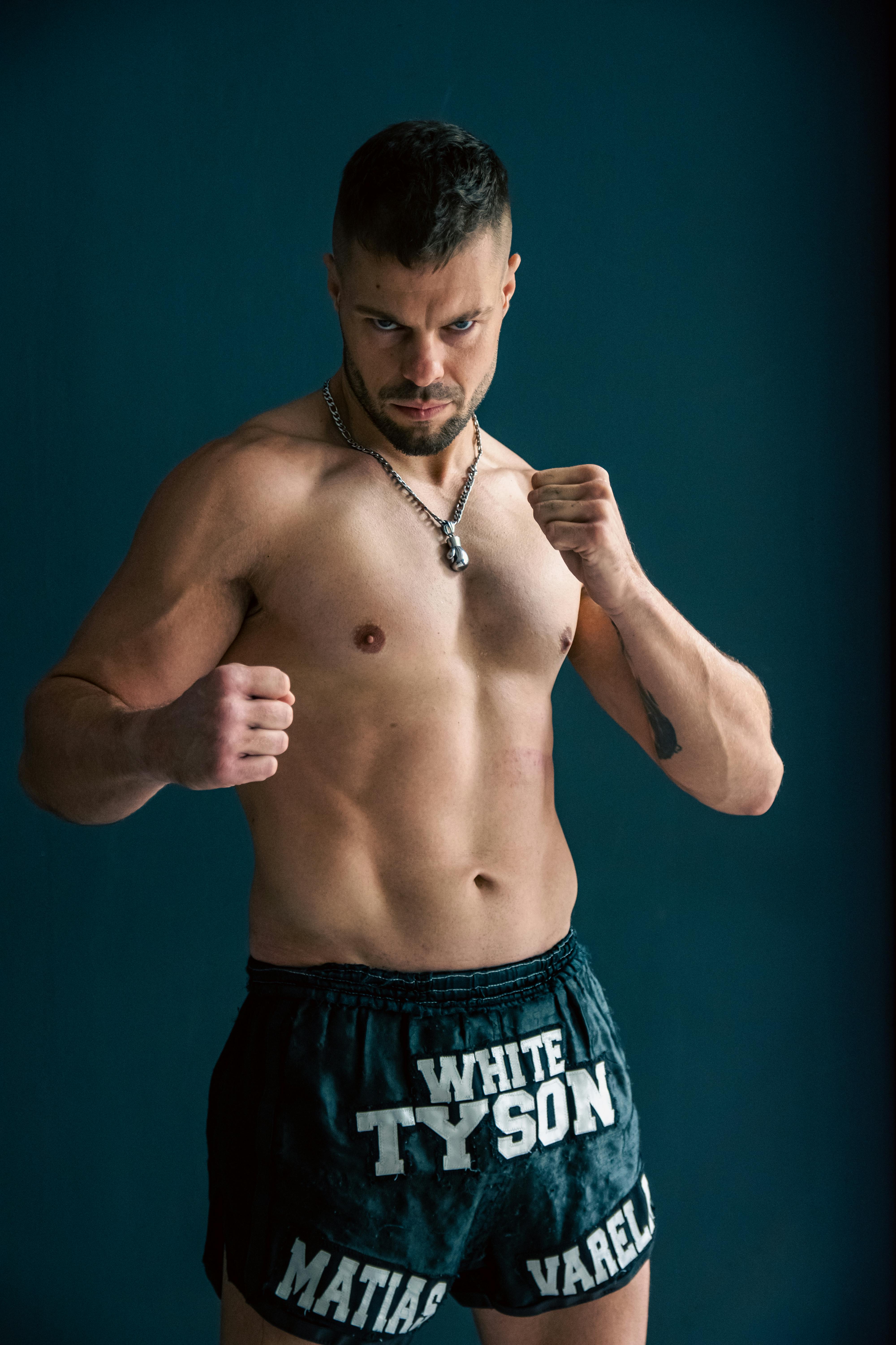 Muscular man in boxing stance, wearing shorts with 'White Tyson' text, indoors.