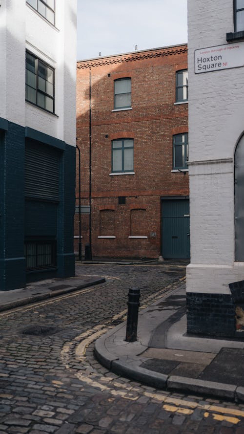 A narrow street with buildings and a brick wall