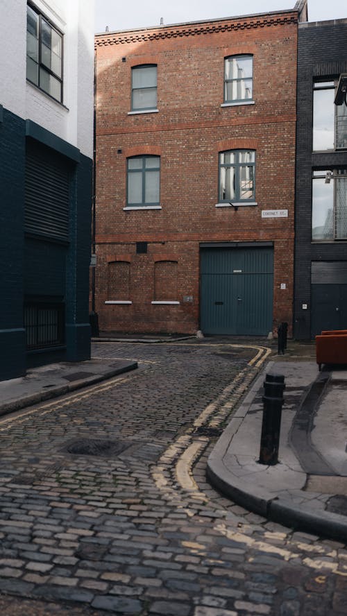 A narrow alleyway with a brick wall and a building