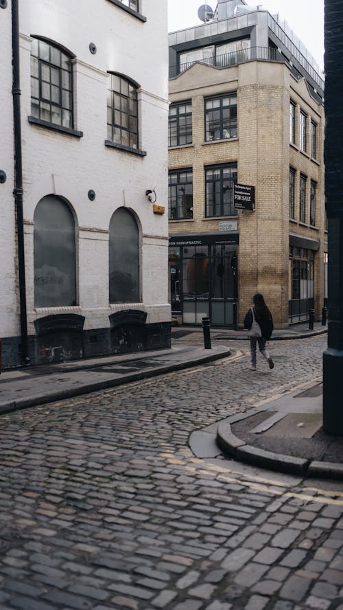 A person walking down a cobblestone street