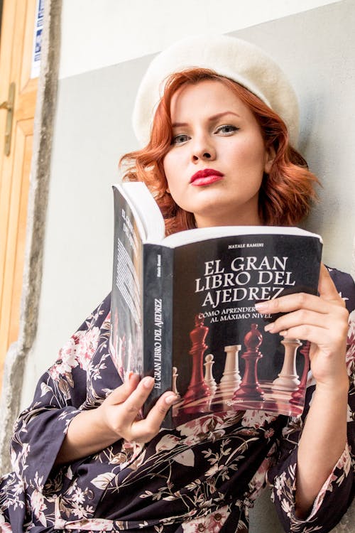 A woman in a hat and dress holding a book