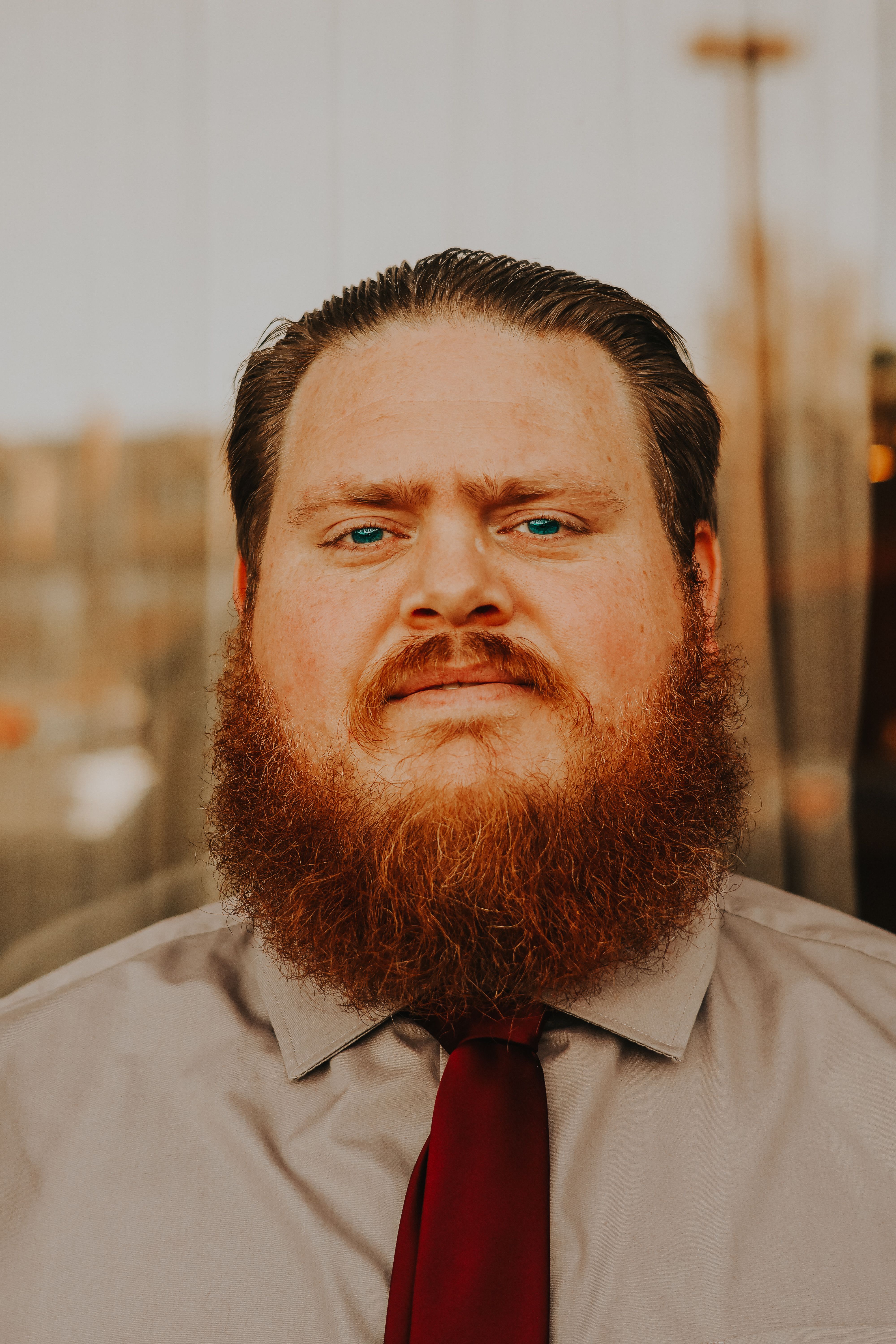 Close-up portrait of a confident man with a beard and tie, wearing a shirt, captured outdoors.