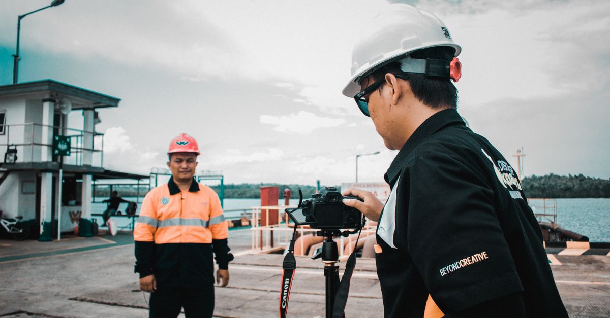 Profissionais com equipamento de segurança gravando vídeo em um local de trabalho