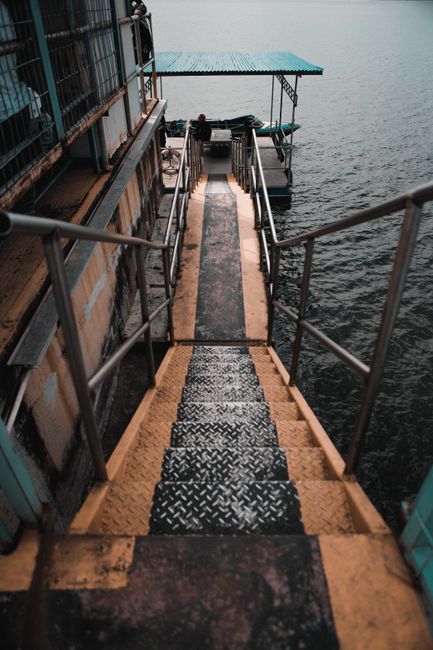 A downward view of metallic steps descending to a lakeside dock, perfect for travel destinations.