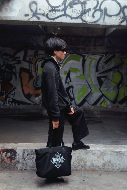 Free Stylish man in black outfit poses against a graffiti wall, embodying urban fashion. Stock Photo