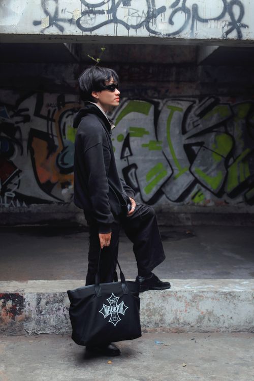 Free Stylish man in black attire poses against vibrant graffiti wall, embodying urban fashion trends. Stock Photo