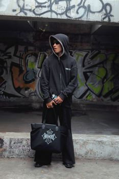 Stylish model in streetwear posing against a graffiti backdrop, showcasing urban fashion trends.