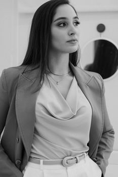 Black and white portrait of a confident woman in business attire with a reflective backdrop.