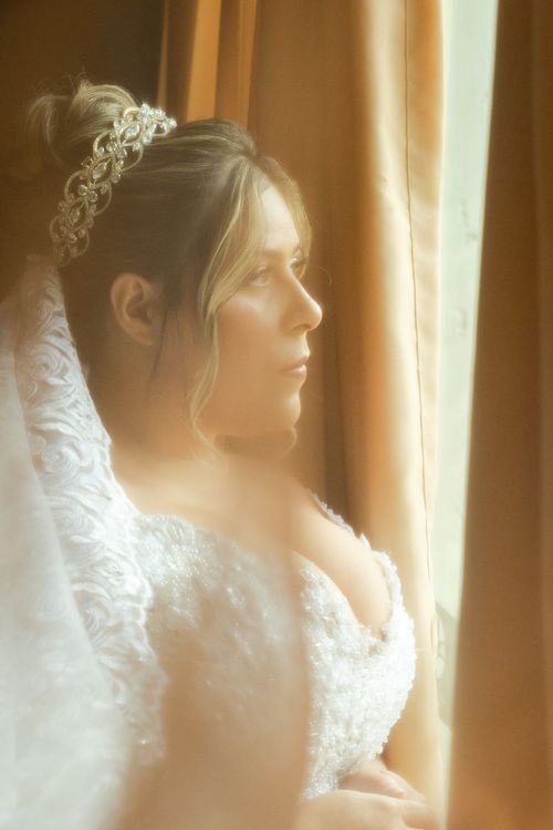 Free Portrait of a bride in a wedding dress gazing out a window in São Paulo, Brazil. Stock Photo