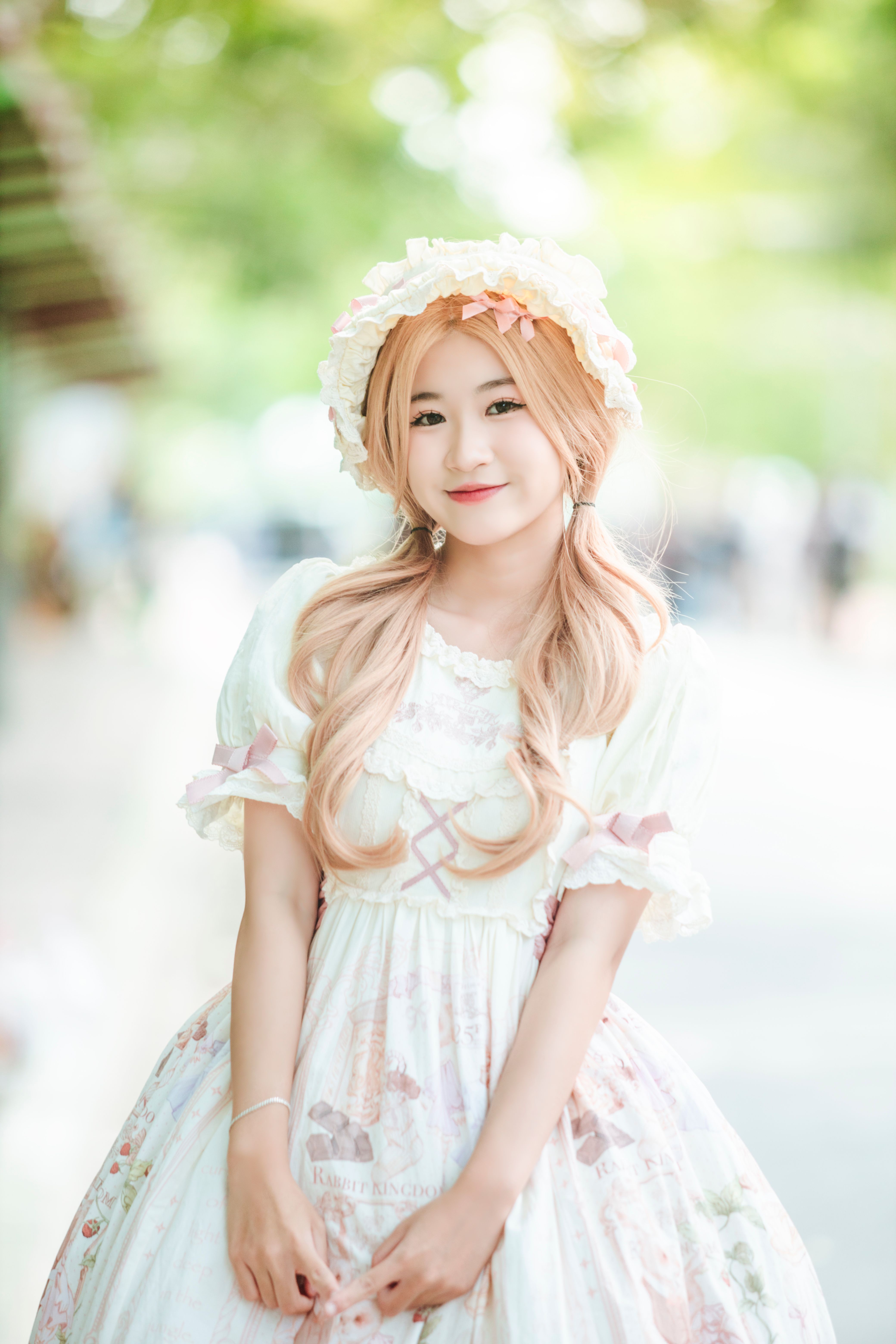 Smiling young woman in a vintage white dress outdoors, exuding elegance and grace.