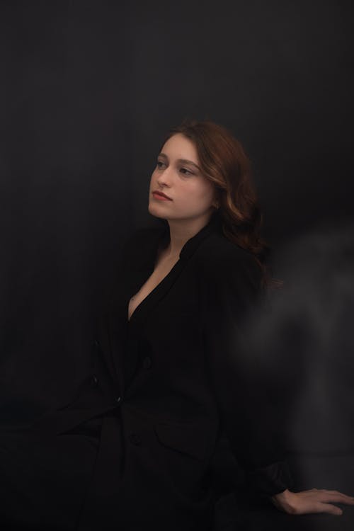 A woman in a black suit sitting on a chair