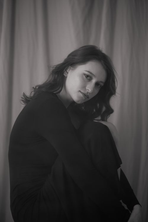 Free Artistic black and white portrait of a woman with long hair sitting indoors. Stock Photo