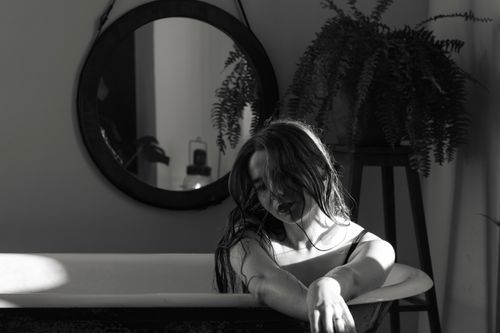 Free Black and white photo of a woman relaxing in a bathtub with soft lighting and shadows. Stock Photo