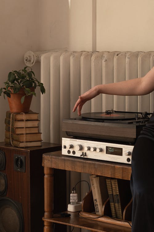 A woman is sitting on a wooden table with a record player