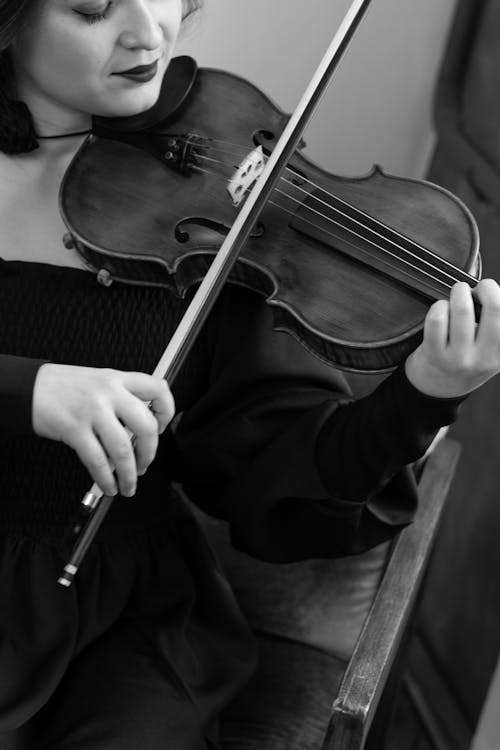 A woman in black and white playing the violin