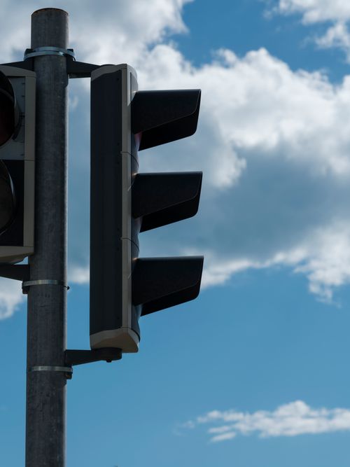 Free Close-up of a traffic light against a bright blue sky, symbolizing urban navigation. Stock Photo