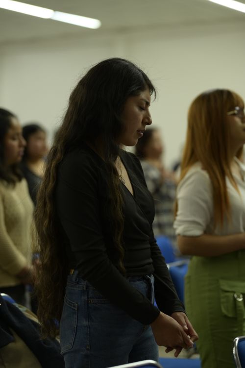 Free A woman with long hair praying in a crowded indoor religious event. Stock Photo