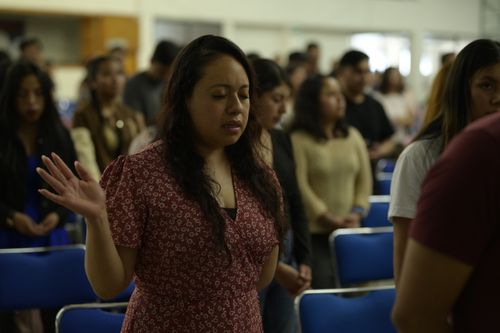 Free A woman with eyes closed prays during a church service in Ciudad de México, surrounded by a congregation. Stock Photo