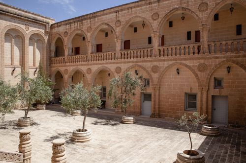 Free Explore the tranquil courtyard of Mor Gabriel Monastery with its historic arches and olive trees in Midyat, Türkiye. Stock Photo