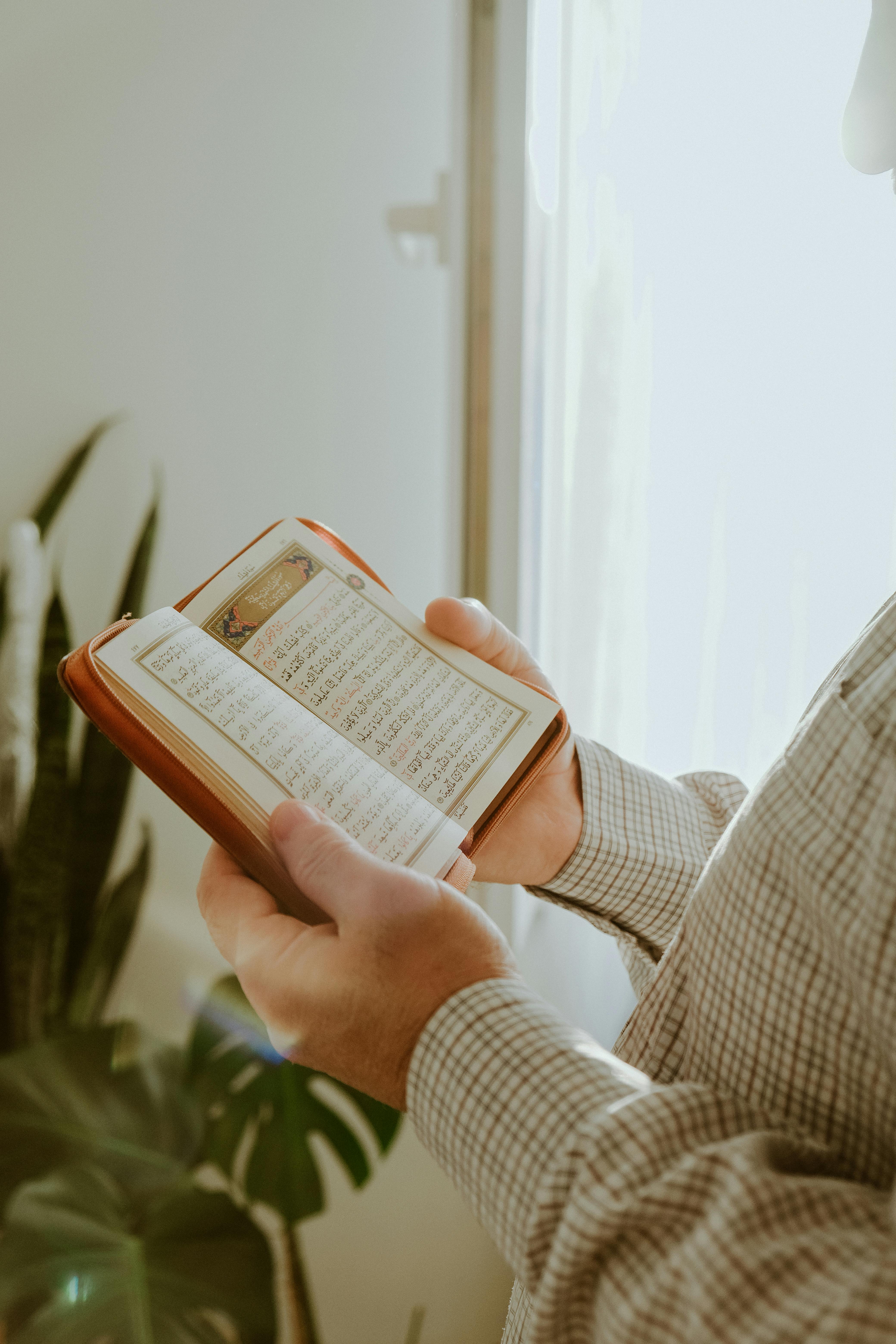 man hands holding book in arabic