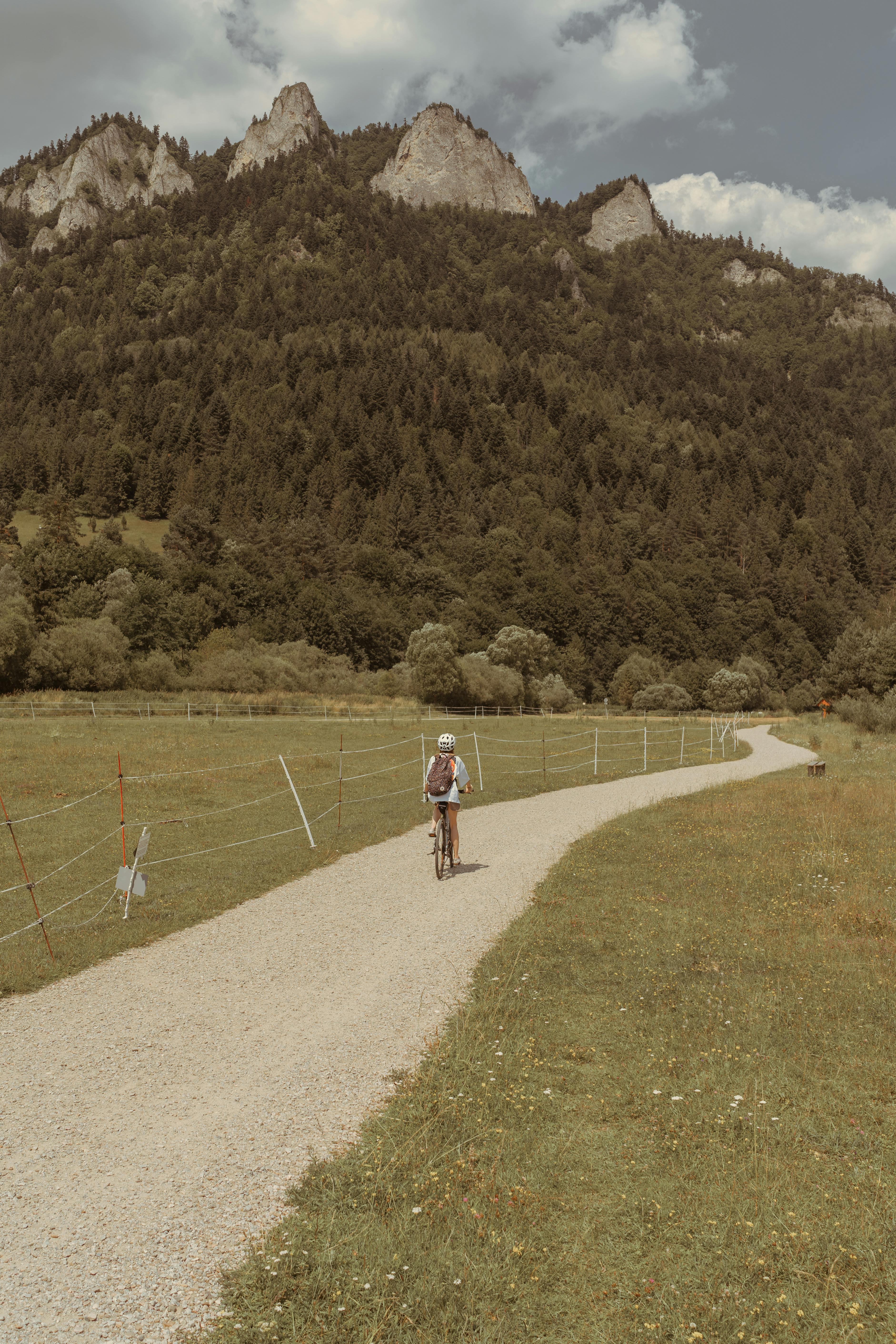 Cyclist on a dirt road in the picturesque Pieniny Mountains, Poland, under a summer sky.