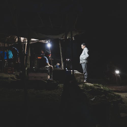 A man standing in front of a tent at night