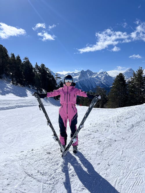 A woman in pink ski gear standing on a snowy slope