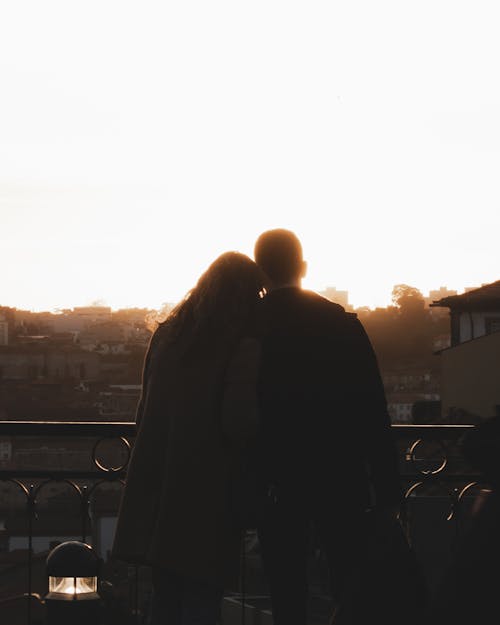 Silhouettes of Man and Woman on Balcony at Dawn