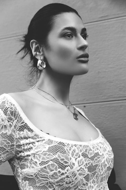 A woman in a white lace top and earrings