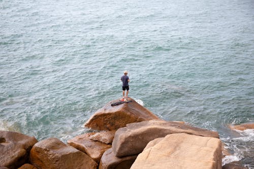 A person standing on a rock near the ocean