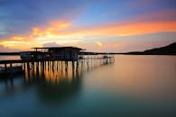 日落时分，平静的水面上倒映着乡村木码头的宁静景色和充满活力的天空