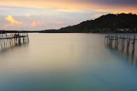 平静的水域、木制码头和远处的山丘映衬着宁静的日落