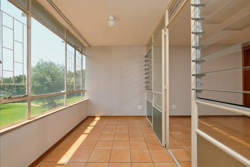 An empty room with a large window and tile floor