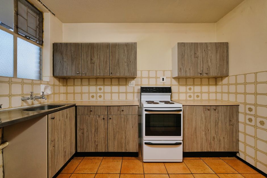 Cozy kitchen interior featuring wooden cabinets, stove, and tiled backsplash.