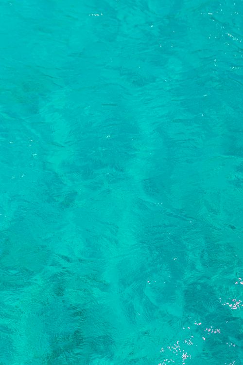 Free A vibrant image of clear turquoise water with subtle ripples, ideal for backgrounds. Stock Photo