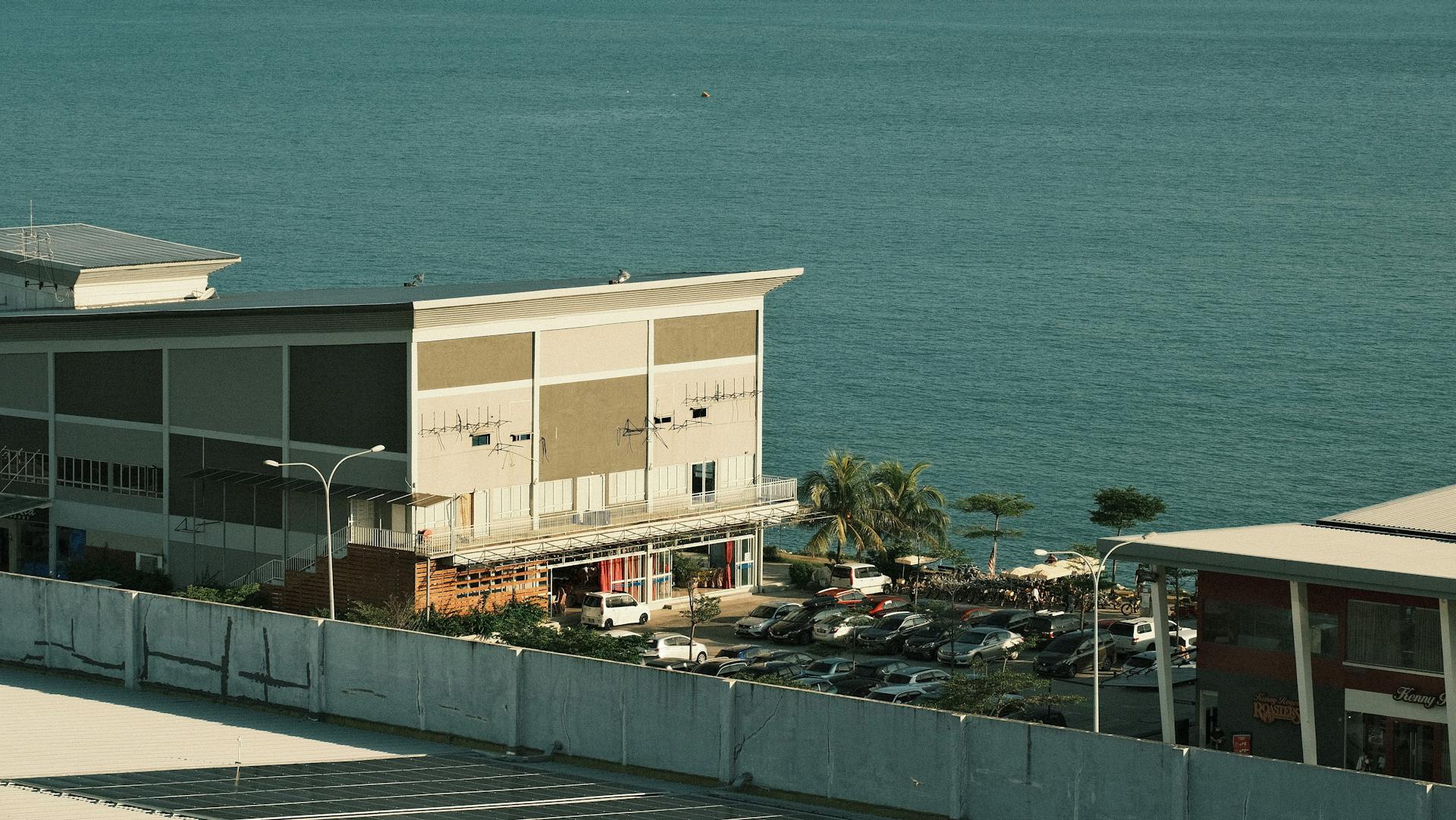 Aerial view of a coastal building and parking lot by the sea in Port Dickson, Malaysia.