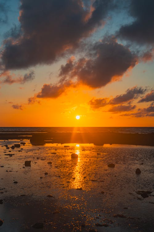 The sun sets over the ocean with clouds in the sky