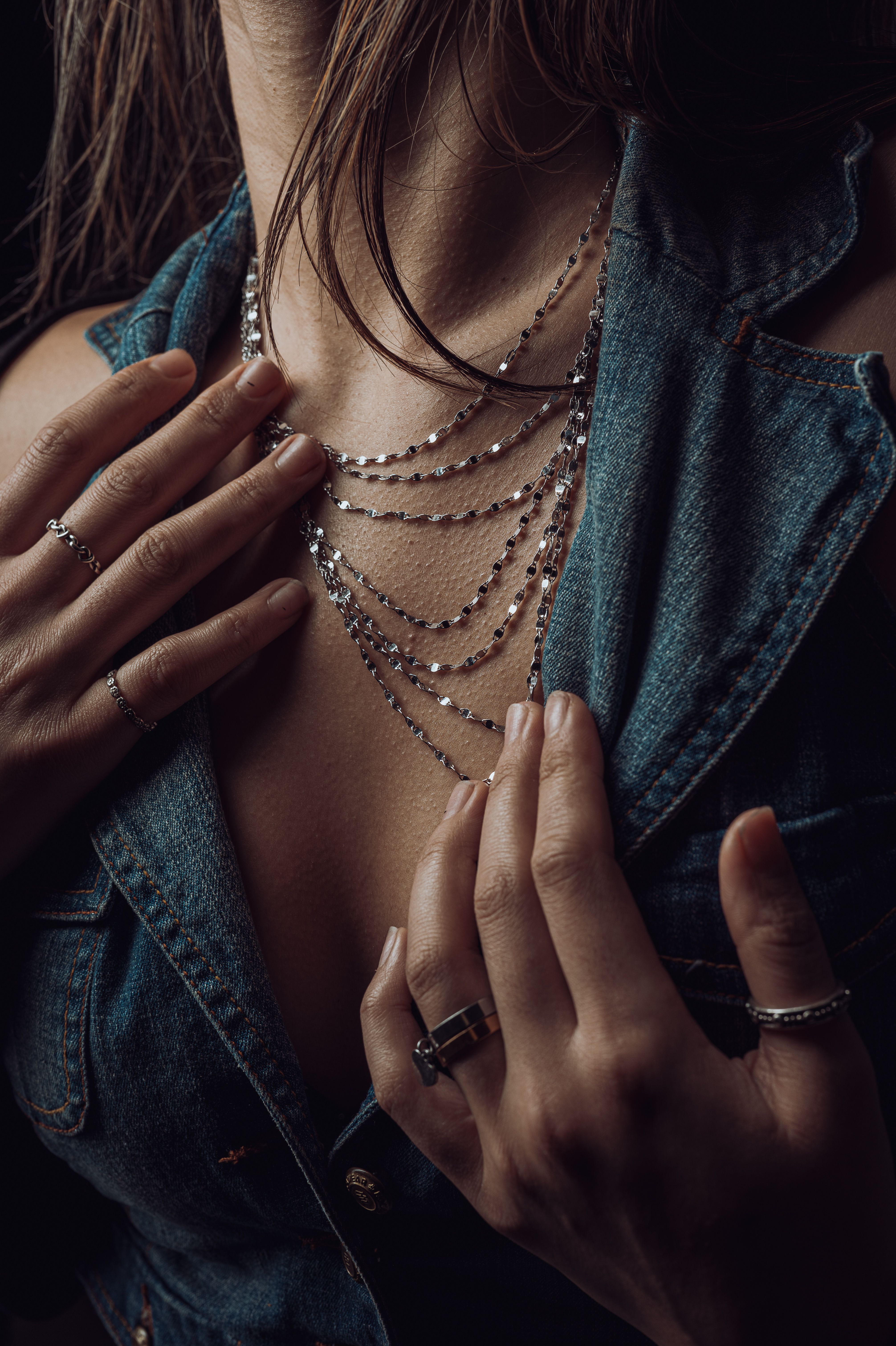Colliers superposés portés avec une veste en jean.