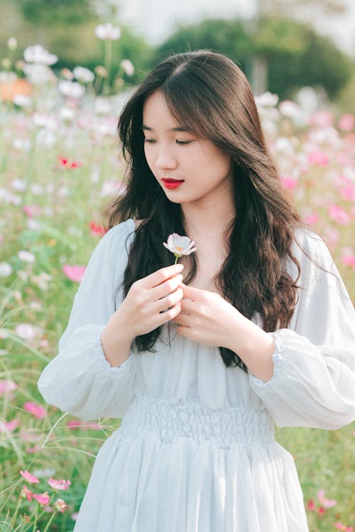 A woman in a white dress holding a flower