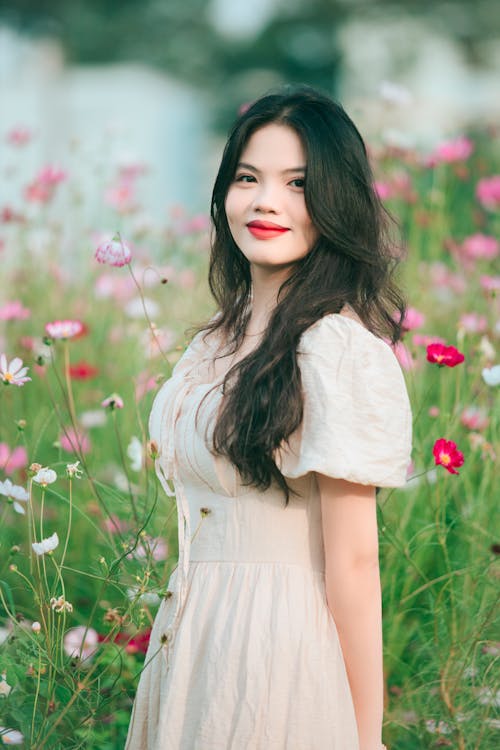 Portrait of Woman in Dress on Meadow with Flowers