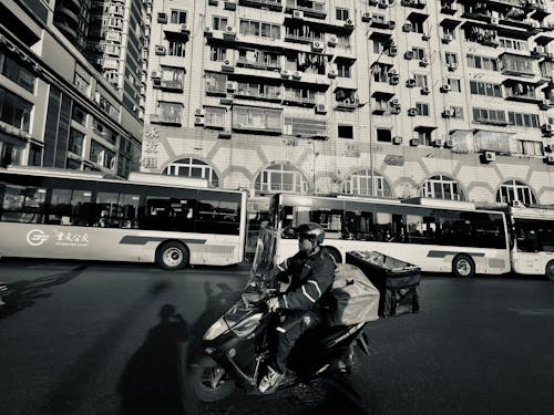 A man riding a motorcycle in front of a bus
