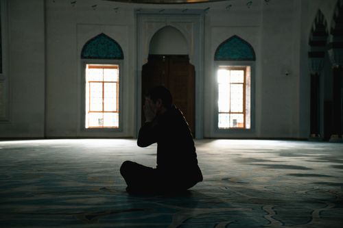 Free A lone figure prays in a serene mosque, embracing tranquility and reflection in the sacred space. Stock Photo