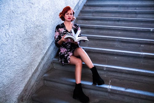 A woman sitting on some stairs reading a book