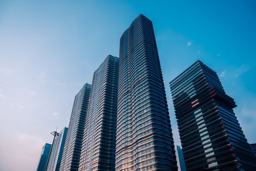 Modern skyscrapers reaching for the sky in Hangzhou, China, captured under a clear blue sky.