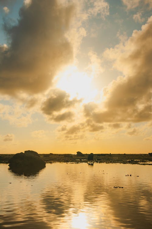 A sunset over the water with clouds in the sky